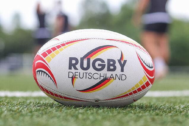 Rugbyball mit Logo und Schriftzug von Rugby Deutschland liegt auf Kunstrasen