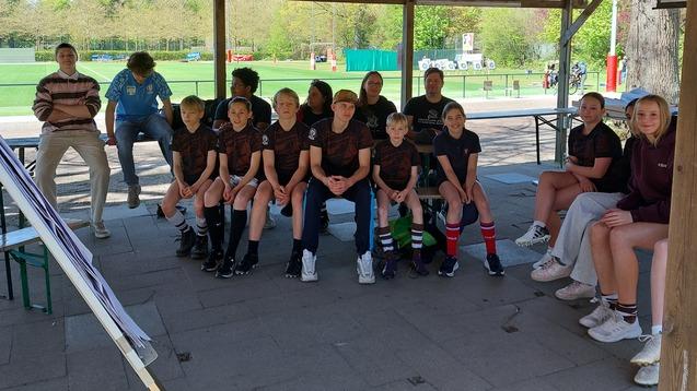 Jungs und Mädchen des FC St. Pauli sitzen während eines Lehrganges für Jungschiedsrichter und Jungschiedsrichterinnen auf Bänken unter einem Carport vor einer Flipchart